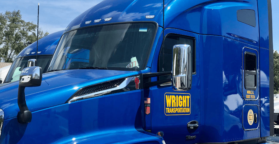 The exterior of a semi-truck cab is shown. It is a royal blue color with the Wright Transportation logo in navy and yellow on the driver's door.